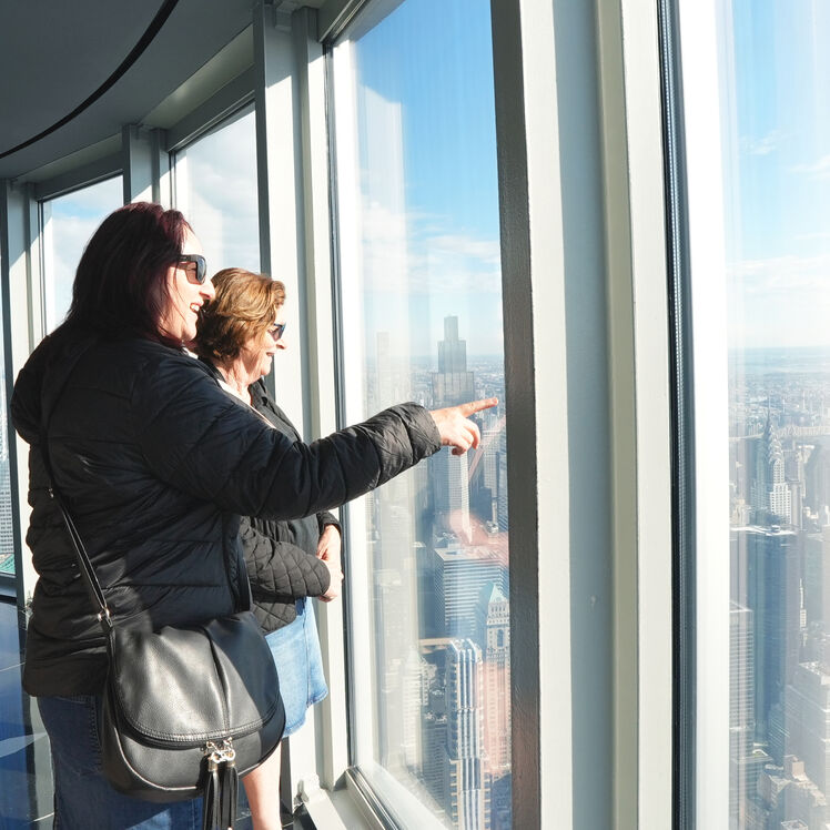 Two women on the 102nd Floor Observatory pointing and looking at the view